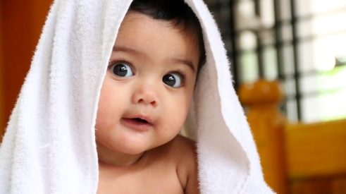 adorable baby with a bath towel over its head